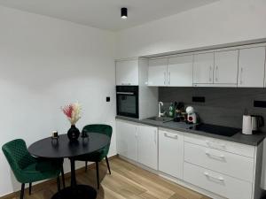 a kitchen with white cabinets and a table with green chairs at Bonaca Residence in Makarska