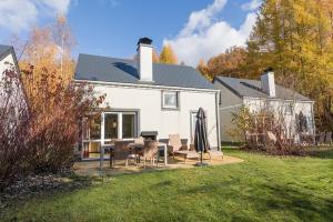 a white house with a table and chairs in the yard at Center Parcs Les Ardennes in Vielsalm