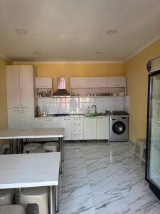 a large kitchen with white cabinets and a dishwasher at Cottage Shara - შარა in Ureki