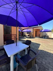a table with a purple umbrella on a patio at Cottage Shara - შარა in Ureki