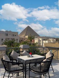 a table and chairs on a balcony with a pyramid in the background at Phoenix Pyramids Inn in Banī Ghālib