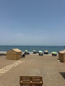 a wooden bench sitting on a beach with umbrellas at Chalets MB in Tarîfa