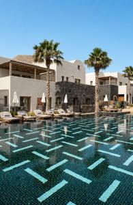 a swimming pool at a resort with palm trees at Radisson Blu Zaffron Resort, Santorini in Kamari