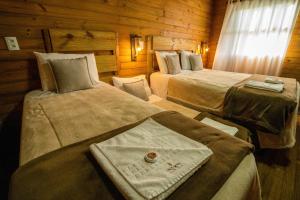 a room with two beds in a log cabin at Pousada Costaneira in Cambará