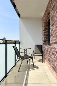 a balcony with a table and chairs on a brick wall at Apartament Stara Fabryka 42 in Włocławek