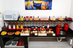 a kitchen with a counter with food and a microwave at Pousada Casa da Fernanda, Suíte Moon in Praia Grande +17 photos