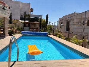 a swimming pool with a yellow chair next to a building at מבט אל הואדי in Abū Ghaush