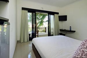 a bedroom with a large white bed and a balcony at Indah Homestay in Seminyak