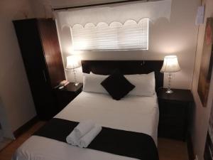 a bedroom with a bed with white sheets and pillows at Feathers Guest House in Welkom +24 photos
