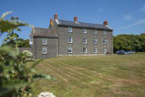 an old building with a grass field in front of it at Picture Cottage in Solva