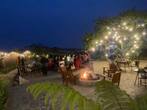 a group of people sitting around a fire pit at night at Charming Home Tà Xùa in Bắc Yên