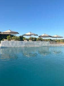 a pool of blue water with umbrellas on a beach at Monte da Fonte in Odemira