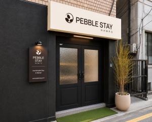 a building with a black door and a sign at 페블스테이 남포점 in Busan