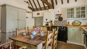 a kitchen with a wooden table with chairs and a stove at Butts Farm in Cirencester