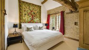 a bedroom with a large white bed and a window at Butts Farm in Cirencester