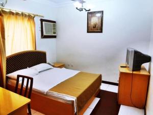 a bedroom with a bed and a tv on a desk at Sun City Hotel in Muscat