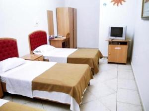 マスカットにあるSun City Hotelのベッド3台とテレビがあるホテルの部屋