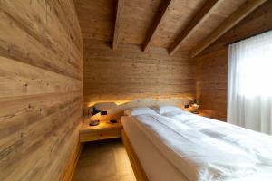a bed in a room with a wooden wall at Chalet Brisi - Luxury & Bergblick in Wildhaus
