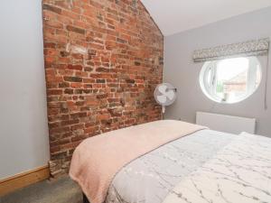 a bedroom with a brick wall and a bed at Barn 1 in Sandbach