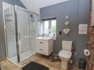 a bathroom with a shower and a toilet and a sink at Barn 1 in Sandbach +13 photos