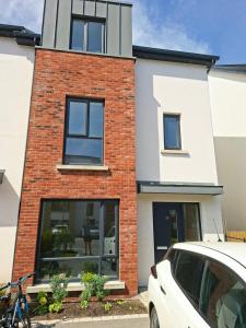 a white car parked in front of a brick building at Spacious ensuite bedroom in Kiltiernan