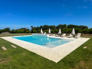 a large swimming pool with lounge chairs and umbrellas at Monte da Fonte in Zambujeira do Mar