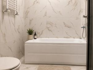 a white bathroom with a tub and a toilet at AVI GARDEN Apartments in Constanţa +35 photos