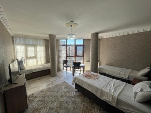 a bedroom with two beds and a television and a table at VAN SERHAT Pansiyon in Ipekyolu
