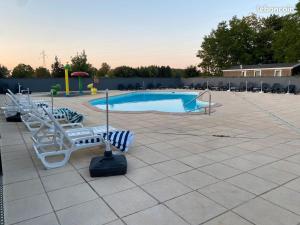 a swimming pool with a bunch of chairs around it at La pépite Rose d'Europapark in Boofzheim