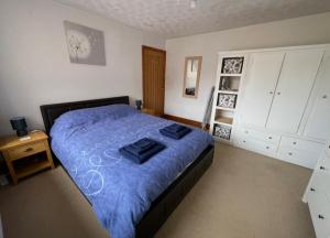 a bedroom with a bed with a blue comforter at The Annexe in Ammanford