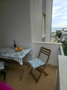 a table and chair on a balcony with a bowl of fruit at Tronca Apartament Kalabria in Marina di Strongoli