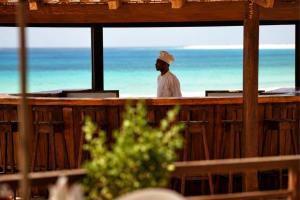 a man standing at a bar near the ocean at Hotel Morabeza in Santa Maria