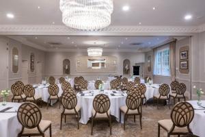 a banquet hall with tables and chairs and a chandelier at Wood Hall Hotel & Spa in Wetherby