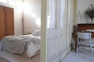 a bedroom with a bed and a chair next to a door at De Waenhuis Cottage in Calitzdorp