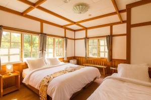 two beds in a room with two windows at Kamishiro Mountain Lodge in Hakuba