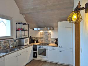 a kitchen with white cabinets and a white refrigerator at L'Hirondelle - Charming flat - in Blotzheim