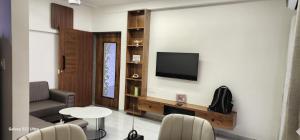 a living room with a television and a table and chairs at Devbhumi Residency in Vadodara