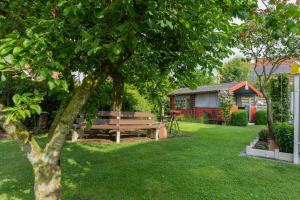 a park bench sitting in the grass near a tree at Ferienwohnung Am Walde 35177 in Hesel