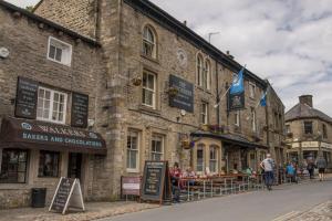 an old stone building with tables and chairs on a street at The Smithy in Kettlewell