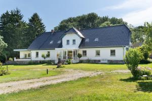 a white house with a black roof at Villa Wiese Störtebecker in Katzow
