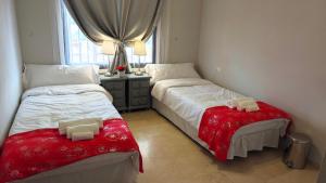 a bedroom with two beds with red sheets and a window at Tango Andaluz - Sunset Ritual Incl in Fuengirola
