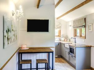 a kitchen with a small island with a tv on the wall at Snow Drop Hut in Alkborough