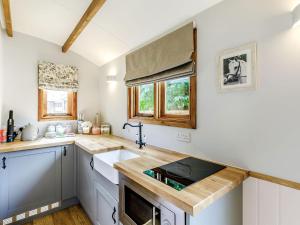 a kitchen with white cabinets and a wooden counter top at Snow Drop Hut in Alkborough +11 photos