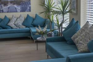 a living room with blue couches and plants at The Beachcroft Hotel, BW Signature Collection in Bognor Regis