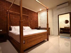 a bedroom with a wooden bed in a brick wall at Mu Homestay Tetebatu in Tetebatu