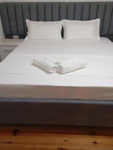 a bed with two white towels on it at Villa K & N in Sarandë