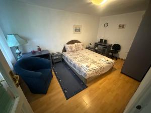 a bedroom with a bed and a blue chair at Apartman Kostadinovic in Pirot +2 photos