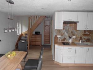 a kitchen with white cabinets and a wooden table with a dining room at Ferienwohnung Buschmühle Schlepzig in Schlepzig +24 photos