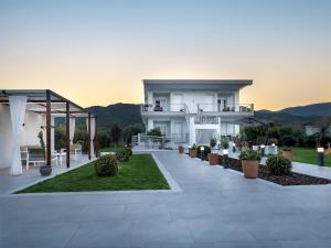 a large white house with a patio with plants at Olive Garden in Olympiada