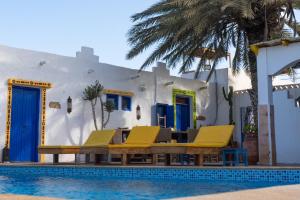 a swimming pool with yellow chairs and a house at Riad Dar Sarah in Taghazout